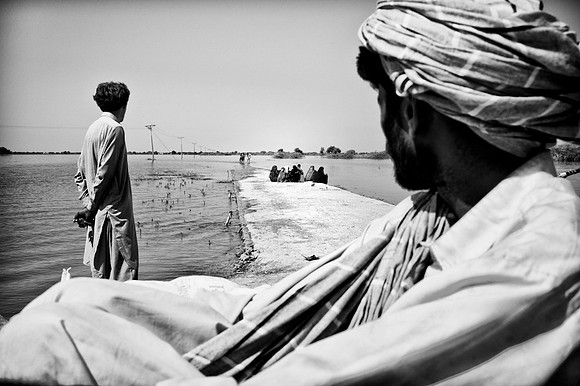 Men walking through flood waters from their villages in search for some form of labour or job