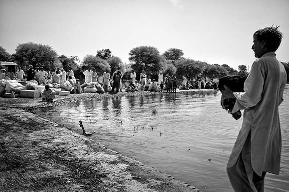 Numerous people and their rations waiting for WFP boats to transport them back to their villages