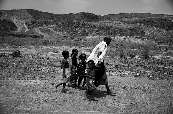 His children walked with him, largely barefoot, through earth so hot, heat emitted and rose from it like the earth itself was catching on fire